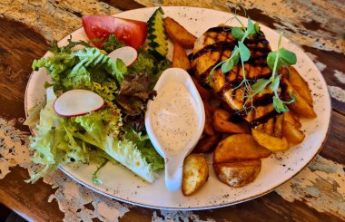 Bir parça ızgara et, ev yapımı patates ve taze sebze salatası..