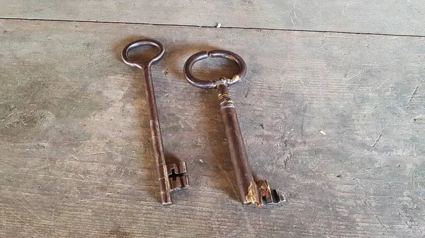 Two large antique keys from an old barn lock on wooden table.