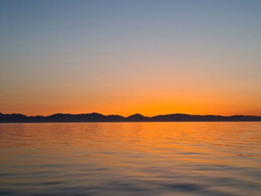 The scarlet sky and the surface of the calm sea after sunset.