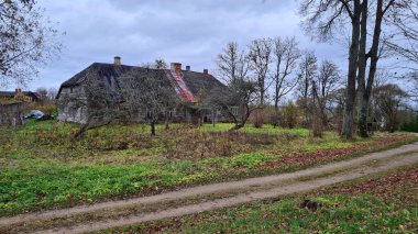 An old wooden dilapidated hut against a gloomy sky in the Latvian village of Dzirciems in autumn 2022.