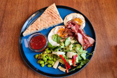 Kızarmış pastırma ve yumurta ve taze sebze salatası kahvaltı için hazırdır..