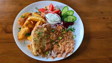 Büyük bir parça domuz eti, patates ve taze sebze salatası..