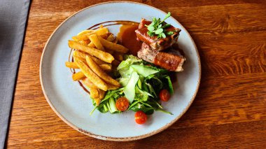 Domuz pirzolası, patates salatası, domates ve sebze tabağı..