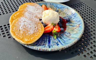 Lezzetli, iştah açıcı, çilekli krepler ve tabakta bir kepçe dondurma..