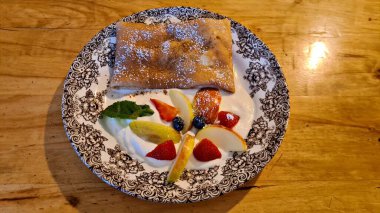 Ekşi kremalı büyük gözleme ve güzel bir tabakta çeşitli meyveler..