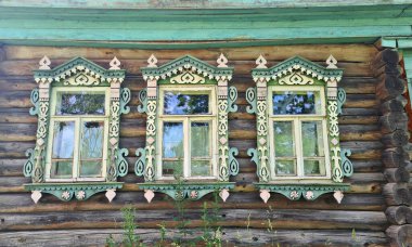 Sahipleri tarafından terk edilmiş eski bir ahşap evin pencereleri ve köyden uzakta uzun otlar..