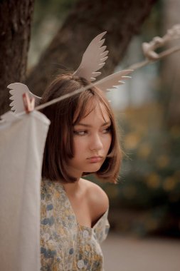 Doğada modası geçmiş bir kız elbiselerini yıkıyor ve asıyor.