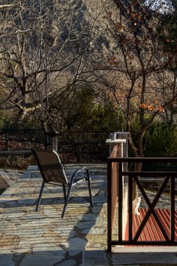 Güneşli bir kış sabahında, bir fincan kahve ve veranda balkonunda dağ manzaralı bir sandalye (Epirus bölgesi, Yunanistan).