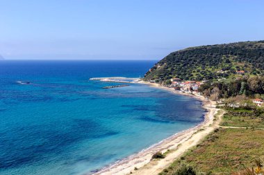 Güneşli bir bahar gününde denizin panoramik manzarası, dağlar ve küçük bir deniz kenti (Kefalonia Adası, Yunanistan)