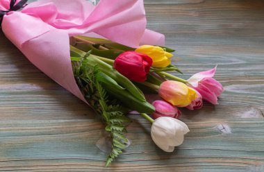 Romantik, renkli lalelerin şenlikli buketi ahşap bir masanın üzerinde..