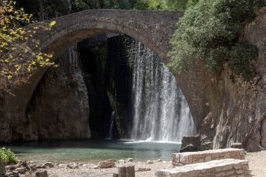 Paleokaria 'nın antik, güzel, taş kemer köprüsü ve dağlardaki şelale (Trikala, Yunanistan)