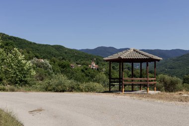 Dağlarda güneşli bir yaz gününde (Orta Yunanistan) köyün yakınındaki dağ yolunun yakınındaki dağlarda dinlenmek için ahşap bir çardak.)