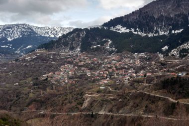 Bulutlu, soğuk ve kış gününde, karlı dağların, sislerin ve Metsovo köyünün (Yunanistan, Epirus) güzel panoramik manzarası