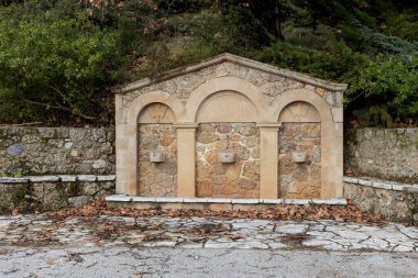 Güneşli bir kış gününde dağlarda soğuk ve berrak su bulunan taştan bir kaynak (Yunanistan, Mora))