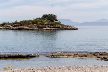 Temiz, güzel, vahşi, çakıl taşı plajı, güneşli bir bahar gününde ada ve deniz manzarası (Yunanistan, Salamis Adası)