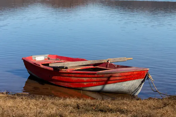 Güneşli bir günde Yunanistan 'ın Karditsa bölgesinde Plastiras Gölü kıyısında bir kırmızı balıkçı teknesi demirler.