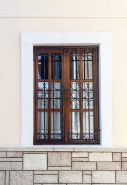 The texture, pattern. The background old beige wall made of natural stone with a window with a grille