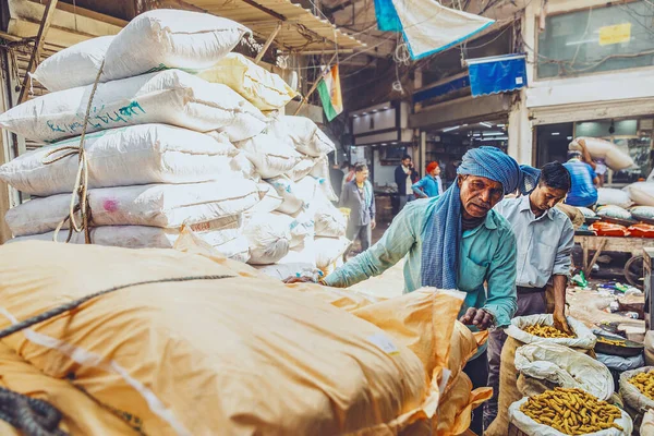 Delhi. Hindistan - 02.28.2023 - Mavi gömlekli bir adam markete torba dolusu baharat boşaltıyor