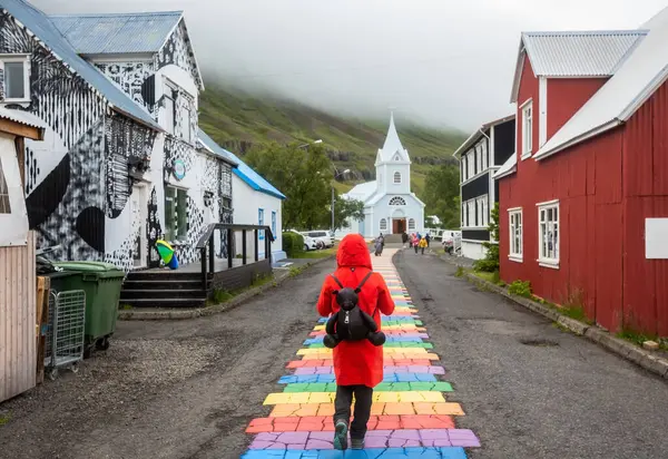 Turist Rød Frakke Går Langs Rainbow Road Landsbyen Seydisfjrur Island - Stock-foto