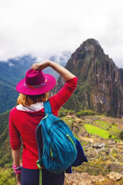 Şapkalı bir kız And Dağları 'ndaki Machu Picchu şehrine bakıyor..