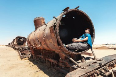 Bir turist eski bir tren vagonunda oturur. Tren mezarlığı (Cementerio de Trenes). Uyuni Bolivya