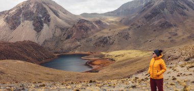 Sarı ceketli bir kız Bolivya 'daki dağlara ve lagüne bakıyor. Uyuni .Tomave. Potosi..