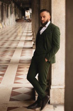 Takım elbiseli şık sakallı adam Venedik, İtalya 'da köşenin arkasında duruyor.