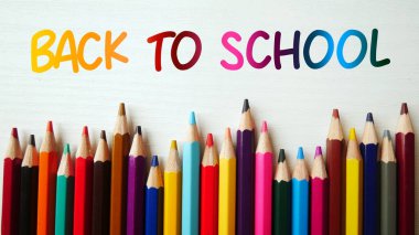 Beyaz mermer arka planda renkli kalem boyaları, renkli kalem kalemleriyle okula dönüş metni..