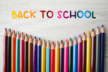 Beyaz mermer arka planda renkli kalem boyaları, renkli kalem kalemleriyle okula dönüş metni..