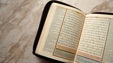 Adamın eli siyah arka planda Kuran 'ın sayfasını açıyor. Kuran Müslümanlar için İslam 'ın kutsal kitabıdır..