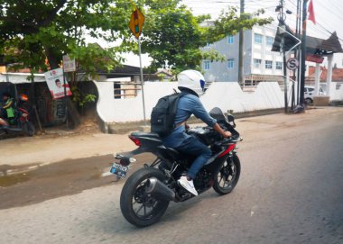 Sürücüler işlek şehir sokaklarında motosiklet sürerler. Güneşli bir günde, şehir caddesinde bir sütun yolcu..