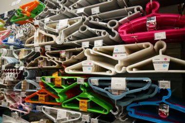 Süpermarketlerde çeşitli elbise askısı ürünleri sergileniyor. Raflarda çeşitli renklerde ve simetrik plastik elbise askıları sergileniyor..
