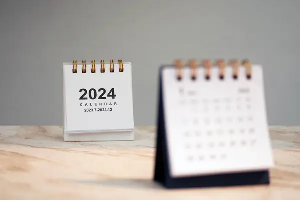 Calendar page January of the year 2024 white color on a white marble table. Concept of planning and setting new strategic goals. Copy space.