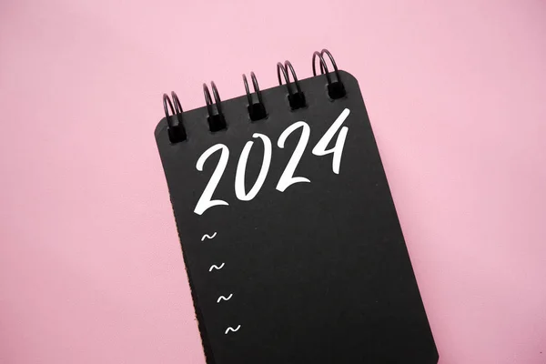 New year resolutions 2024 on black spiral notebook. 2024 goals list with notebook. Resolutions, plan, goals, action, checklist, idea concept. New Year 2024 resolutions, copy space