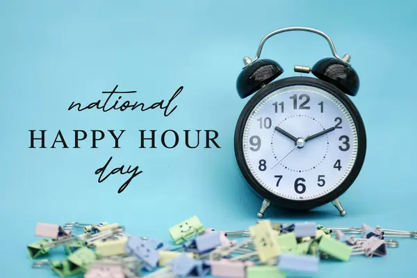 Happy Hour Day, National Hour Day on November 12. An Alarm clock with funny paperclips on a blue background.
