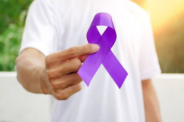 Lüks mor bir kurdeleyi tutan bir el. Pankreas kanseri bilinçli mor kurdele. Kanser farkındalığı kavramı.