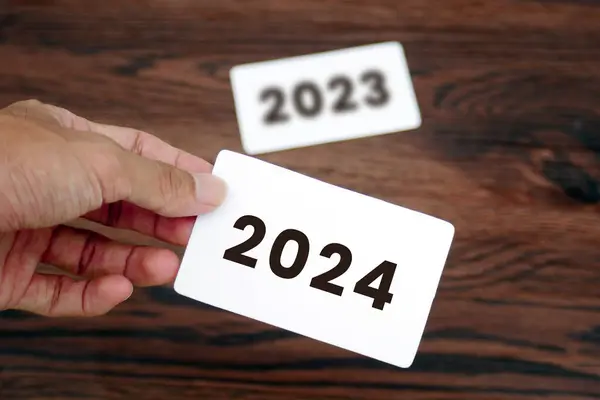 The hand takes the 2024 card leaving the 2023 card behind it.