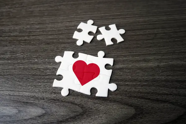 Jigsaw puzzle pieces in form of heart on a background. The concept of a complementary relationship, solving love problems together, charity, donation, helping concept. Perfect match, reunion.