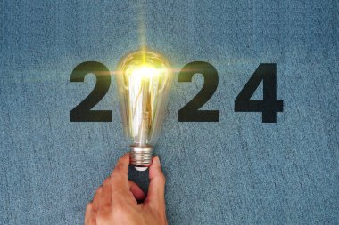 Işıldayan 2024 takvimi, yaratıcı trend ampulü iş adamı eliyle ışıldıyor. Dijital ağ ve lüks arka plan. Mutlu yıllar 2024 Ampullü tebrik kartı.