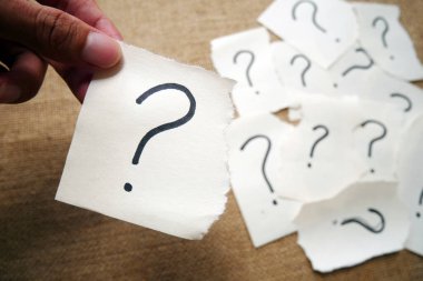 Soru işareti kağıdı. Çuval bezi arka planında soru işareti olan yırtık kağıt el ele tutuşması