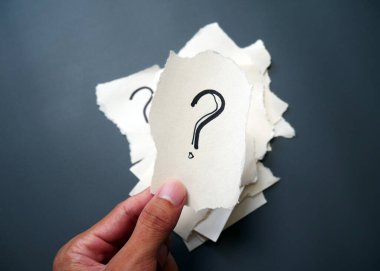 Soru işareti kağıdı. Çuval bezi arka planında soru işareti olan yırtık kağıt el ele tutuşması