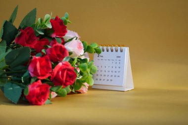 Şubat 2024 tarihli masa takvimi güllü altın bir arkaplan üzerine.