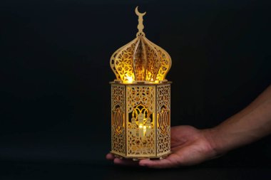 Koyu arkaplanda İslami oymalar olan altın parlayan ahşap Ramazan feneri. Mutlu Ramazanlar. Önemli İslami bayramlar. Afiş fotoğrafı veya İslami bayram tebrik kartı.