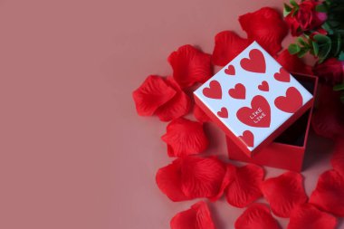 Sevgililer Günü hediye kutusu. Sevgililer Günü afişi tasarımın kutlu olsun. Pembe arka planda hediyeler ve güller var. Boşluğu kopyala.