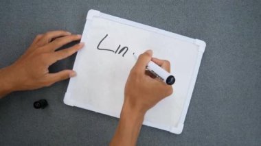 Lincoln 'ün doğum günü yazılı beyaz tahtaya yazı yazan bir adam. Düz kopya alanının üst görünümü.