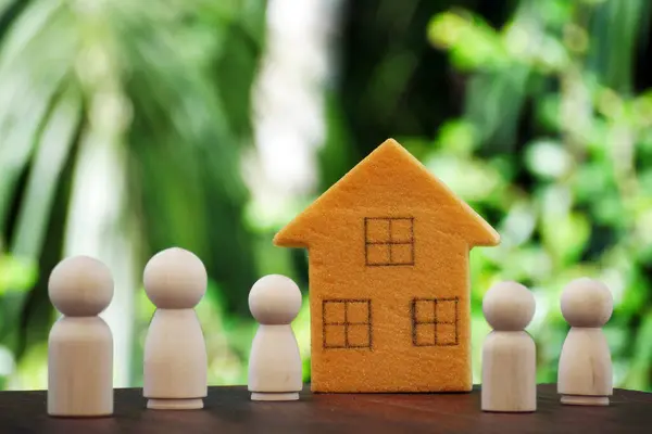 Miniature family house and wooden dolls. Concept of Protection and safety, Home Security, property insurance, home, happy family, child sponsorship, mental health, domestic violence and social distance. Copy space.