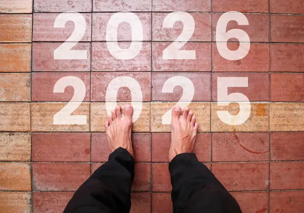 The text 2025 is written on the brick road and the male runner prepares to welcome the new year. Concept of new year 2025, beginning of success, challenges or career path and change.