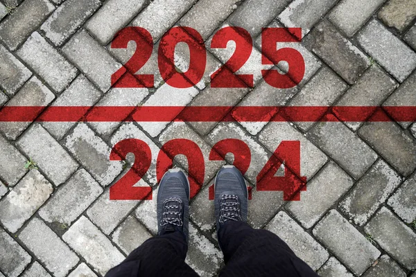 The text 2025 is written on the brick road and the male runner prepares to welcome the new year. Concept of new year 2025, beginning of success, challenges or career path and change.