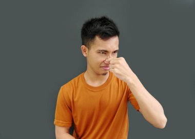 Genç adam koku yüzünden burnunu parmaklarıyla kapatıyor.