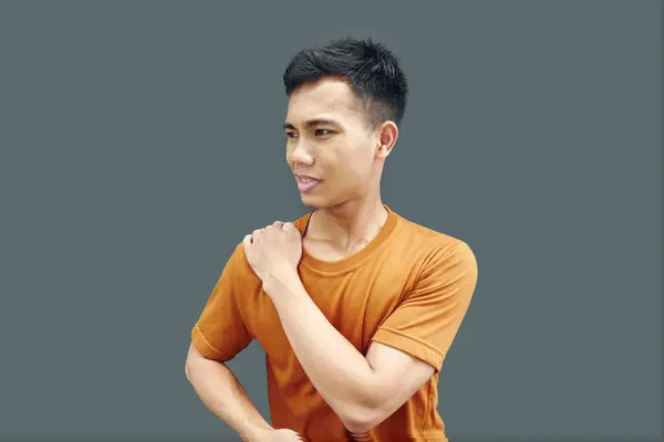 Man massaging stiff shoulders, tired sad man rubbing tense muscles to relieve joint shoulder pain, isolated on blank background. Concept of central nervous system disorders, fibromyalgia.